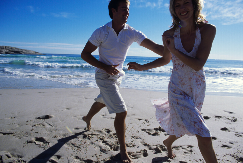 Young man chasing woman on beach